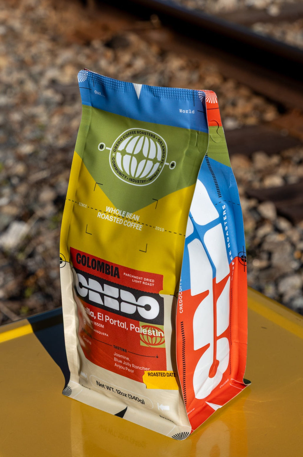 Colorful coffee package on a yellow surface with train tracks in the background