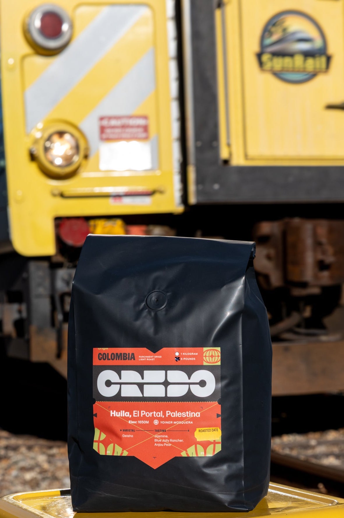 Bag of Credo coffee on a yellow platform with a train in the background