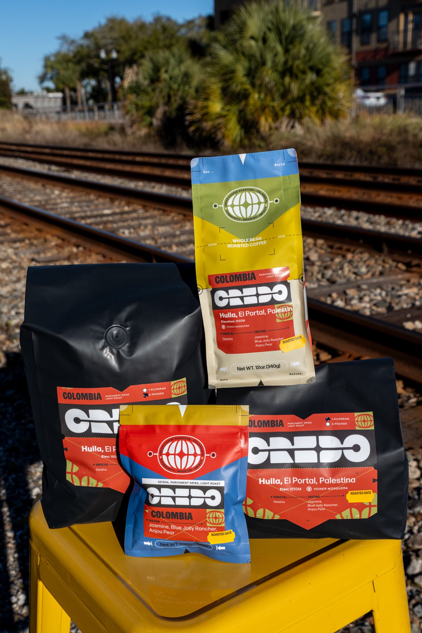 Credo coffee packages on a yellow stool with train tracks in the background