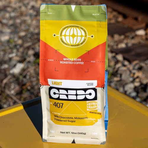 CREDO coffee bag on a yellow surface with train tracks in the background