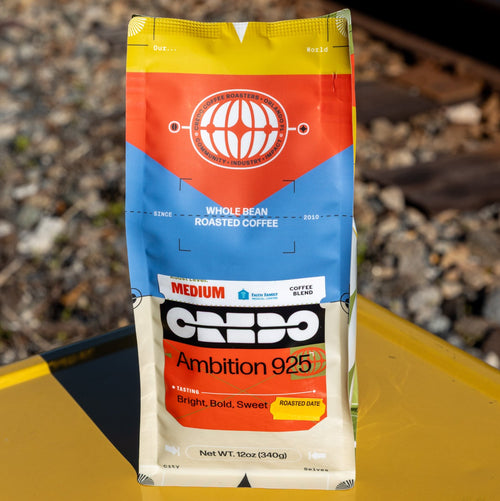 CREDO Coffee bag on a yellow surface with train tracks in the background