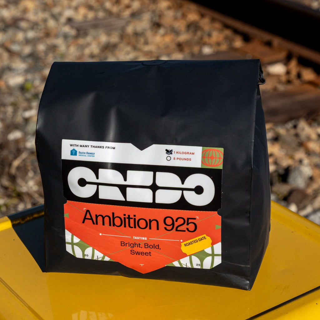 CREDO Ambition 925 coffee bag on a yellow surface with train tracks in the background
