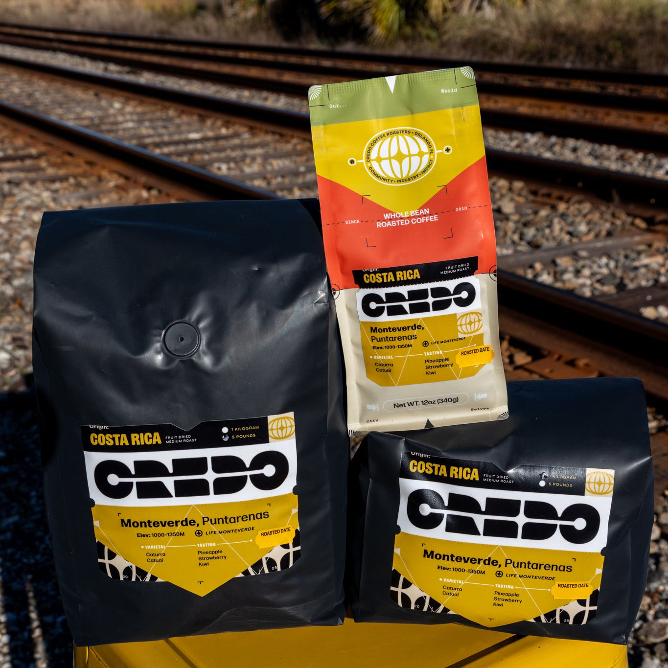 Credo coffee bags on a yellow stool with train tracks in the background