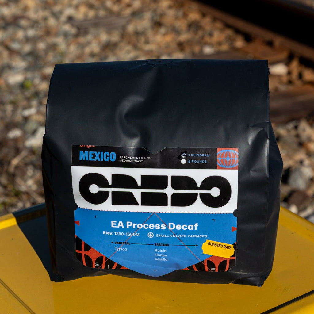 Coffee bag with CREDO branding on a yellow surface with train tracks in the background