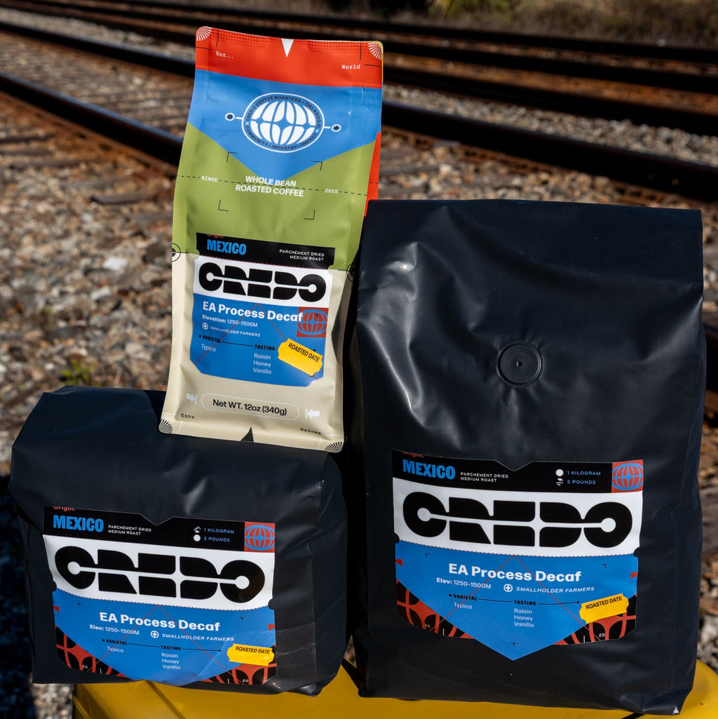 Three bags of CREDO coffee on a yellow stool with train tracks in the background