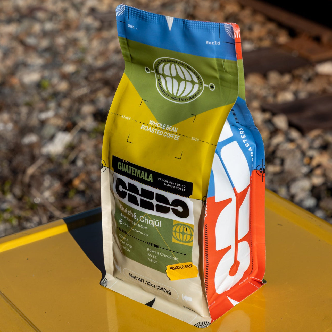 CREDO Coffee bag on a yellow surface with train tracks in the background