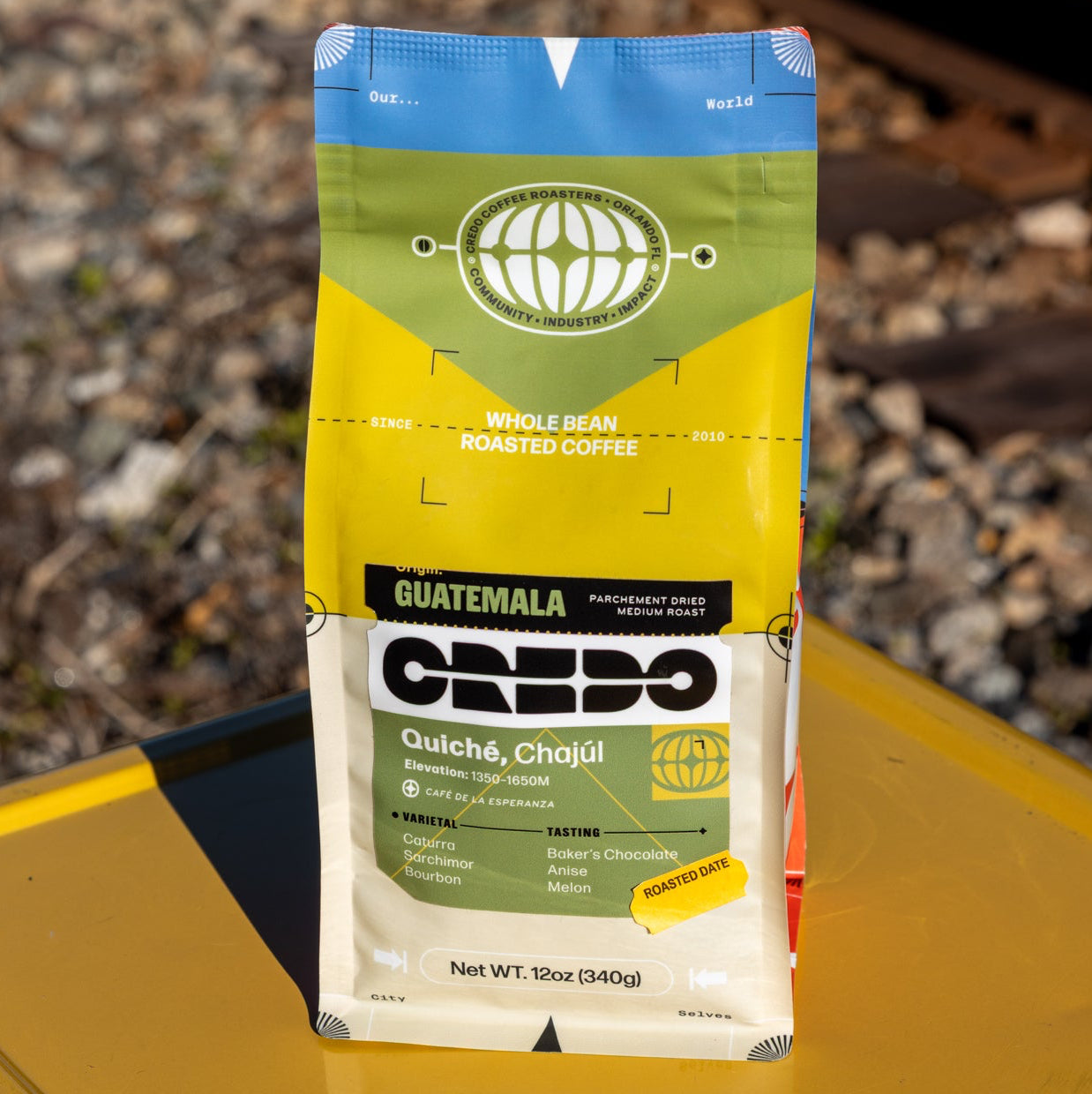 CREDO Guatemala coffee package on a yellow surface with train tracks in the background