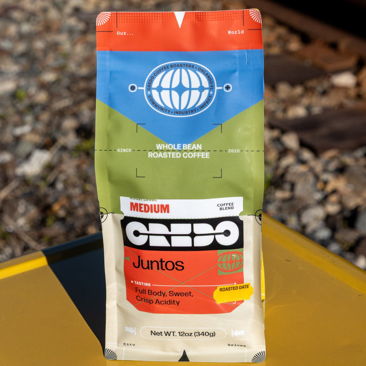 CREDO coffee bag on a yellow surface with train tracks in the background