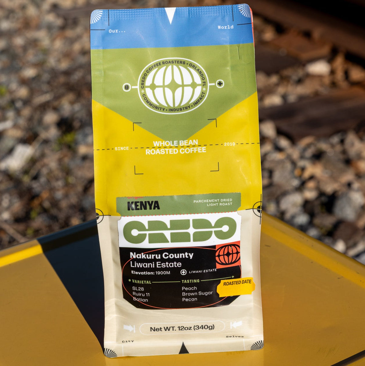 CREDO coffee package on a yellow surface with train tracks in the background