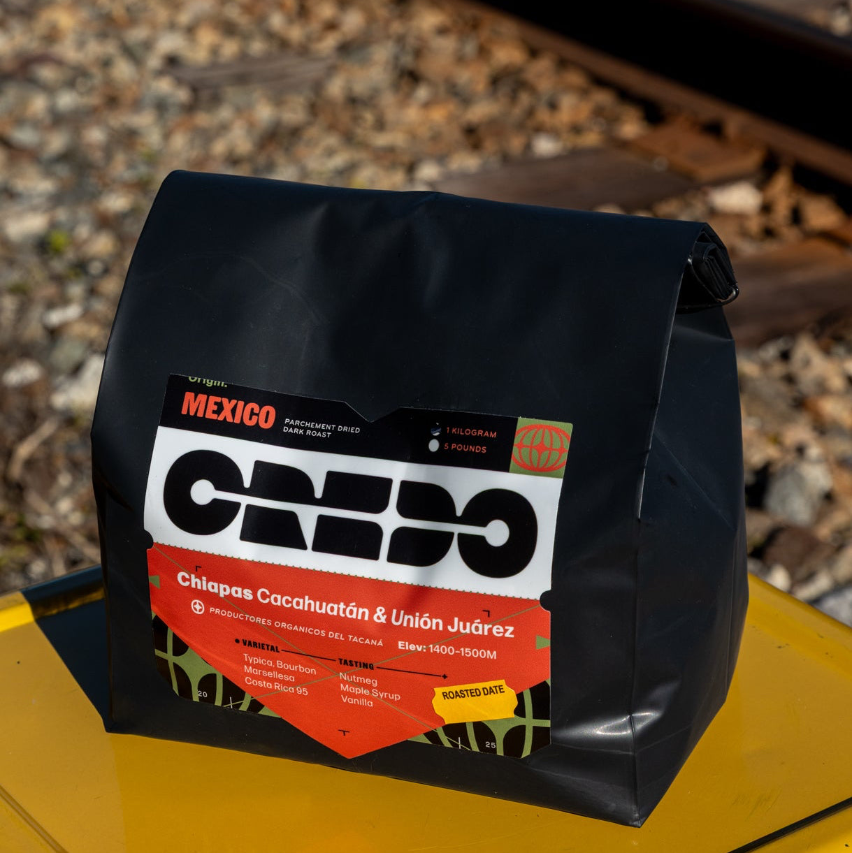 Black bag with CREDO branding on a yellow surface with train tracks in the background