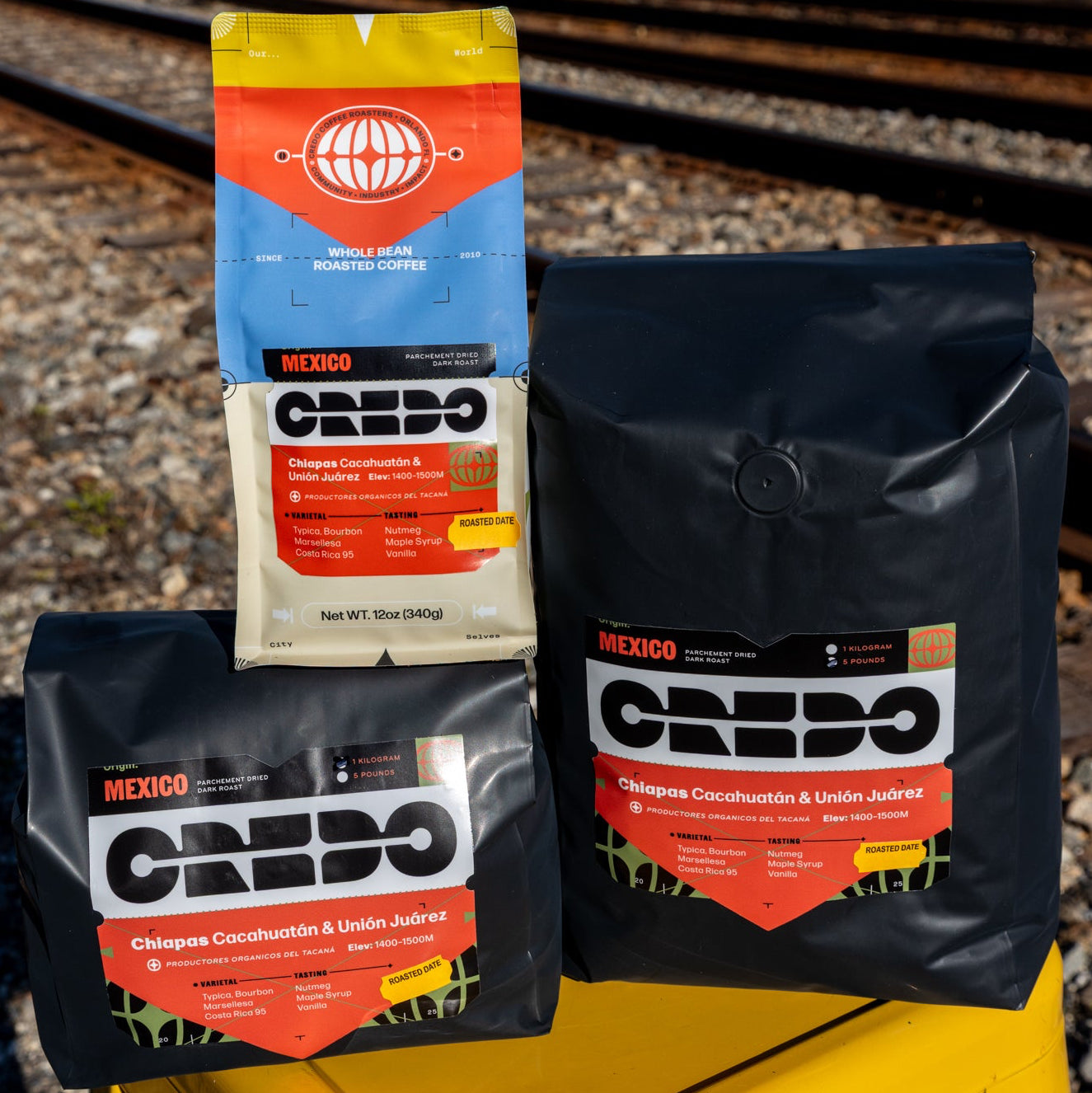 Credo coffee bags on a yellow stool with train tracks in the background